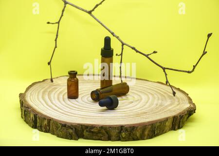 Maquette de flacons en verre brun avec couvercle compte-gouttes sur panneau en bois. Flacons en verre vides avec pipette, fleur d'hortensia séchée sur fond jaune. Concept o Banque D'Images