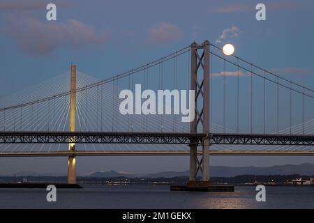 Une pleine lune se couche sur Queensferry Crossing et Forth Road ponts à l'heure bleue, Firth of Forth, Écosse, Royaume-Uni Banque D'Images