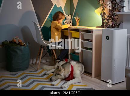 Purificateur d'air dans la chambre des enfants avec un enfant allergique et un chien Banque D'Images