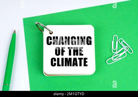 Concept écologique et industriel. Sur une surface blanche se trouve une feuille de papier verte, un stylo et un carnet avec l'inscription - changement du climat Banque D'Images