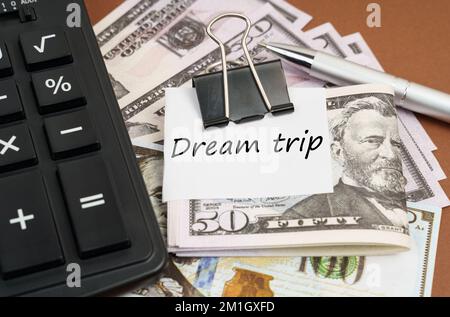 Concept financier et commercial. Sur fond marron se trouve une calculatrice et des dollars sur un clip avec une inscription sur papier - Voyage de rêve Banque D'Images