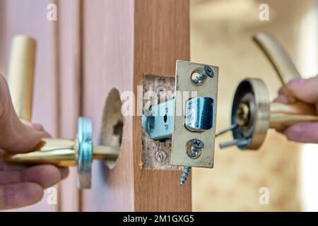 Fixation d'une poignée de porte défectueuse avec loquet sur une porte intérieure. Banque D'Images