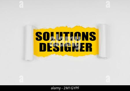 Concept commercial et financier. Une fenêtre est faite dans le papier, où sur un fond jaune l'inscription - Solutions Designer Banque D'Images