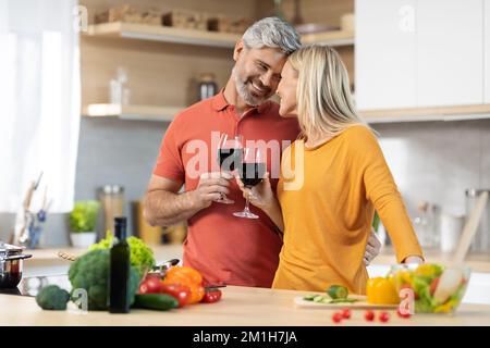 Lier le couple mature boire du vin tout en préparant le dîner Banque D'Images