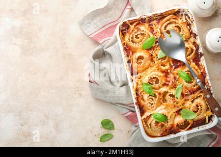 Lasagnes. Pâtes de lasagne faites maison rotolo cuire avec sauce tomate, fromage à la crème et basilic sur une poêle blanche sur fond d'ardoise légère, de pierre ou de béton. JE Banque D'Images