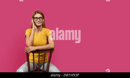 Souriante élégante femme blanche d'âge moyen blonde dans une ambiance décontractée, les lunettes sont assis sur la chaise et l'espace est vide Banque D'Images