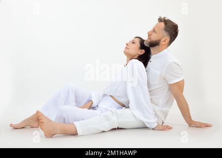 Famille sportive portant des vêtements blancs assis sur le sol après l'entraînement, se détendre, regardant sur fond blanc. Amour. Banque D'Images