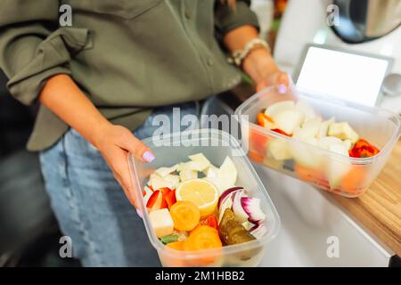 Les mains non reconnaissables d'une femme de culture tiennent deux boîtes contenant des fruits et des légumes frais.portions dans des boîtes jetables Banque D'Images