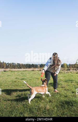 Grande jeune femme jouant avec son chiot et appréciant le moment dans la nature. Jouets pour animaux Banque D'Images