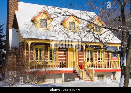 1978 réplique construite de l'ancien 1800s jaune avec garniture orange maison en rondins de style Canadiana en hiver. Banque D'Images