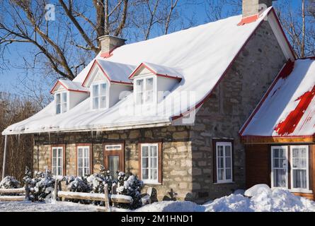 Ancienne maison en pierre de campagne de style cottage Canadiana 1826 avec toit en tôle rouge en hiver. Banque D'Images