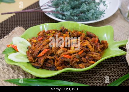 Pampis Tongkol/Cakalang, plat de fruits de mer traditionnel de Manado, de poisson râpé piquant, servi sur une assiette verte Banque D'Images