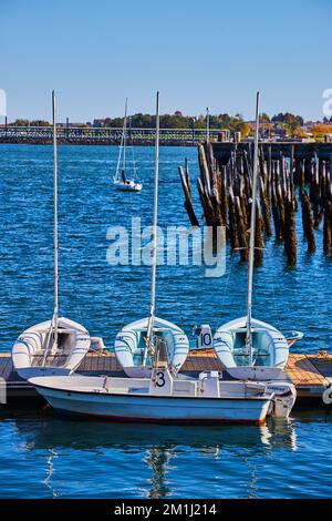 Trio de petits bateaux blancs sur le quai avec de vieux pilings en arrière-plan Banque D'Images