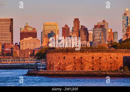 Governors Island Castle Williams depuis les eaux de la ville de New York, lumière du coucher de soleil à l'heure d'or Banque D'Images