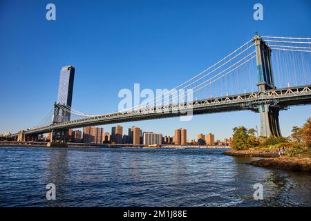 Vue sur l'ensemble du pont de Manhattan depuis Brooklyn dans la ville de New York sur les eaux avec un ciel bleu Banque D'Images