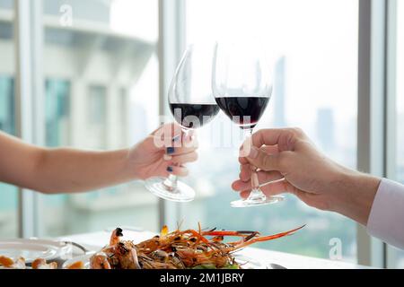 Les mains du jeune couple tenant avec un verre de vin applaudissent ensemble dans le restaurant pour la célébration, l'homme et la femme datent avec romantique et rel Banque D'Images