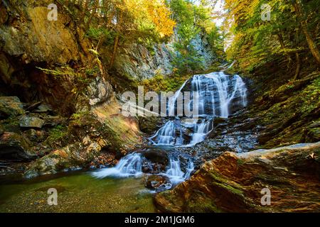 Les feuilles d'automne couvrent les gorges rocheuses avec une cascade qui fait rage et les arbres dans le feuillage de pointe Banque D'Images