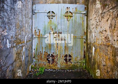 Ancienne entrée de la mine avec des murs en ciment et une énorme porte en acier rouillé Banque D'Images