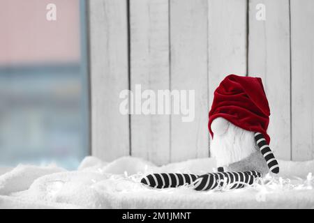 Jouet gnome de Noël sur tissu blanc sur fond de bois clair Banque D'Images