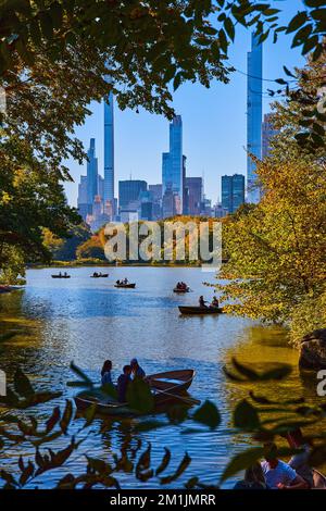 New York City Central Park étang avec des bateaux et de grands bâtiments de la ville en arrière-plan Banque D'Images