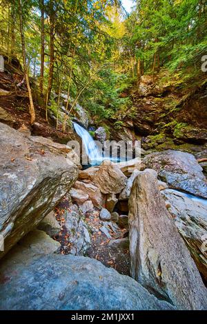 De grands rochers près d'une superbe cascade avec des eaux bleues et des falaises couvertes d'arbres d'automne Banque D'Images