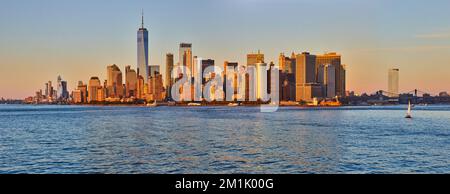 Superbe lumière dorée au-dessus de la ligne d'horizon panoramique du sud de Manhattan depuis les eaux Banque D'Images
