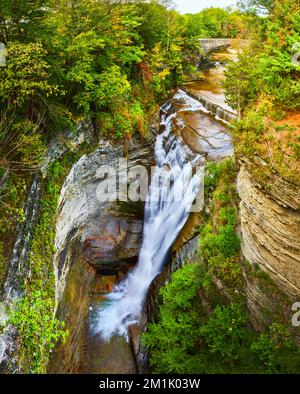 Superbe grande chute d'eau dans des gorges profondes avec pont en pierre en arrière-plan Banque D'Images