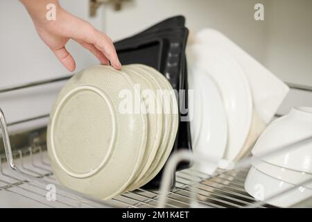 Main de la femme qui prend des assiettes pour servir le dîner Banque D'Images