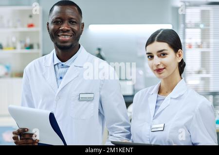 Portrait à la taille de deux professionnels de la médecine ethnique debout dans un laboratoire scientifique et regardant l'appareil photo Banque D'Images