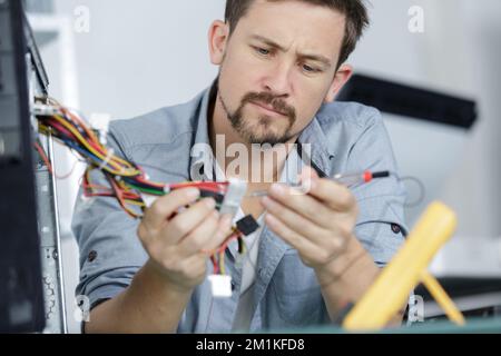 un travailleur de sexe masculin fixe des câbles pc Banque D'Images