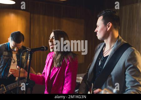 Groupe enregistrant un nouvel album. Gros plan intérieur moyen d'un groupe composé de trois adultes caucasiens dans un studio d'enregistrement. Photo de haute qualité Banque D'Images