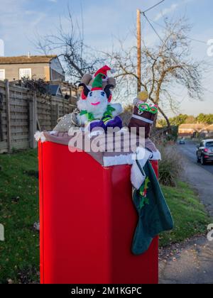 Créatures tricotées ou pourpres sur une boîte postale rouge, village de Piddington, Northamptonshire, Royaume-Uni Banque D'Images