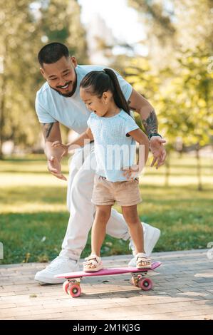 Jolie petite fille à bord d'un skate board dans un parc Banque D'Images