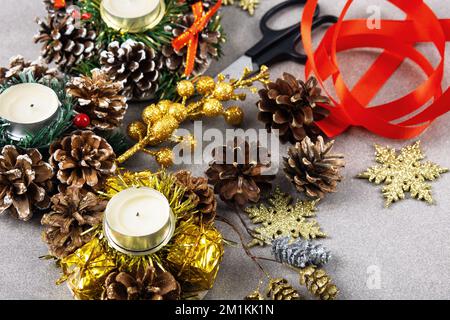 Set pour faire des décorations de Noël sur la table de ciseaux, bijoux, ruban de satin, cônes et bougies sur un fond en bois Banque D'Images