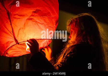 jolie fille avec ballon de papier orange fortune dans les mains préparées pour le voler loin Banque D'Images