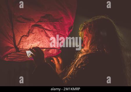 jolie fille avec ballon de papier orange fortune dans les mains préparées pour le voler loin Banque D'Images