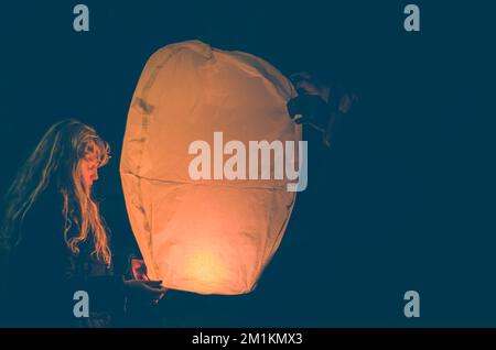 jolie fille avec ballon de papier orange fortune dans les mains préparées pour le voler loin Banque D'Images