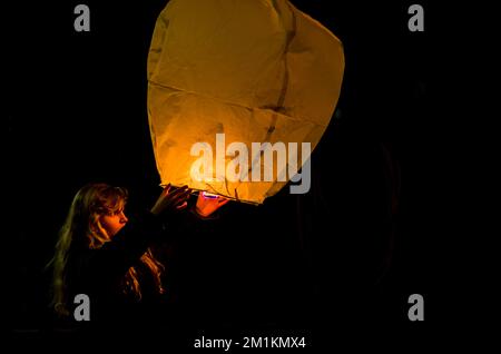 jolie fille avec ballon de papier orange fortune dans les mains préparées pour le voler loin Banque D'Images