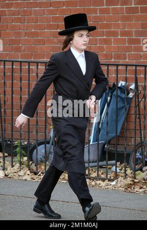 Un jeune juif orthodoxe avec un long peyot et des vêtements noirs marche brusquement à l'extrémité nord de Lee Avenue à Brooklyn, New York. Banque D'Images