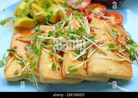 Gros plan de tofu grillé et de salade de légumes, garni de microverts Daikon Banque D'Images