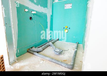 Installation d'eau dans la nouvelle salle de bains non finie, tuyaux d'égout en PVC gris exposés montés sur l'endroit pour une cabine de douche. Banque D'Images