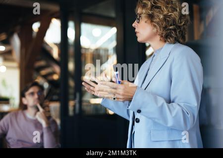 femme d'affaires dirigeant une réunion de conférence. Professionnelle féminine présentant une idée à ses collègues. Discussion en équipe dans un bureau moderne. Banque D'Images