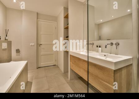 une salle de bains moderne avec deux lavabos et un grand miroir sur le mur à côté du lavabo est une baignoire blanche Banque D'Images