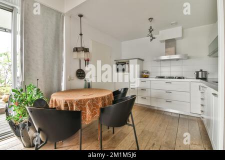 une table à manger et des chaises dans une cuisine avec une fenêtre ouverte donnant sur le patio extérieur donnant sur le jardin Banque D'Images