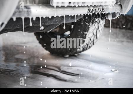 Nettoyage de voiture avec de la mousse. Gros plan sur les gouttes de mousse blanche qui s'écoulant d'une voiture dans un lave-auto. Mise au point sélective Banque D'Images