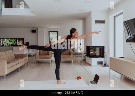 Jeune belle femme exercice, étirement et pratiquer le yoga avec le formateur via vidéoconférence à Bright Sunny House. Un style de vie sain Banque D'Images