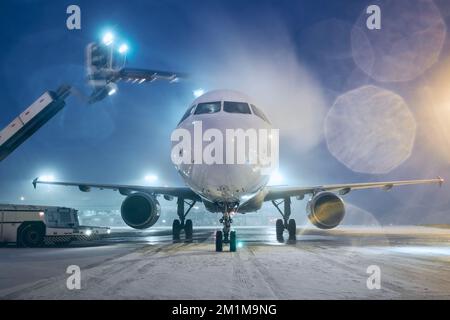 Dégivrage de l'avion avant le vol. Nuit d'hiver à l'aéroport pendant les chutes de neige. Banque D'Images