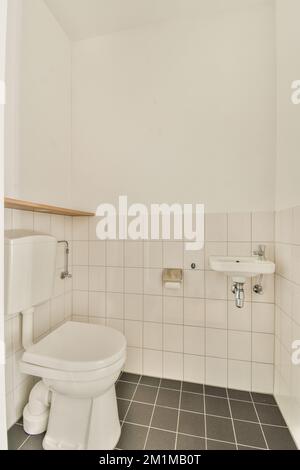 Intérieur de la petite salle de bains avec lavabo et toilettes avec murs blancs et plancher en damier Banque D'Images