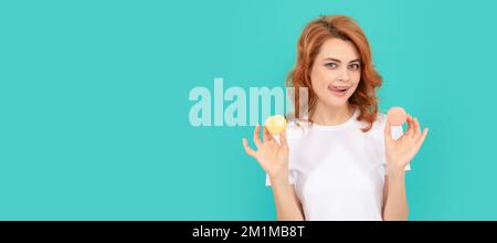 bonne fille tient doux macaron cookie français sur fond bleu. Femme isolé visage portrait, bannière avec maquette d'espace de copie. Banque D'Images