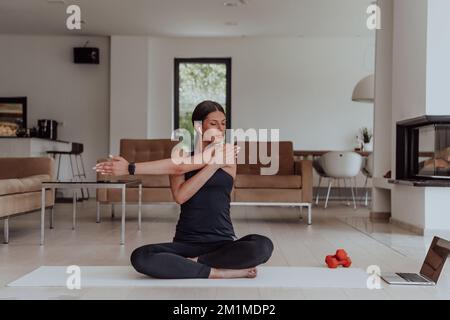 Jeune belle femme exercice, étirement et pratiquer le yoga avec formateur via vidéoconférence dans lumineux Sunny Loft Appartement. En bonne santé Banque D'Images